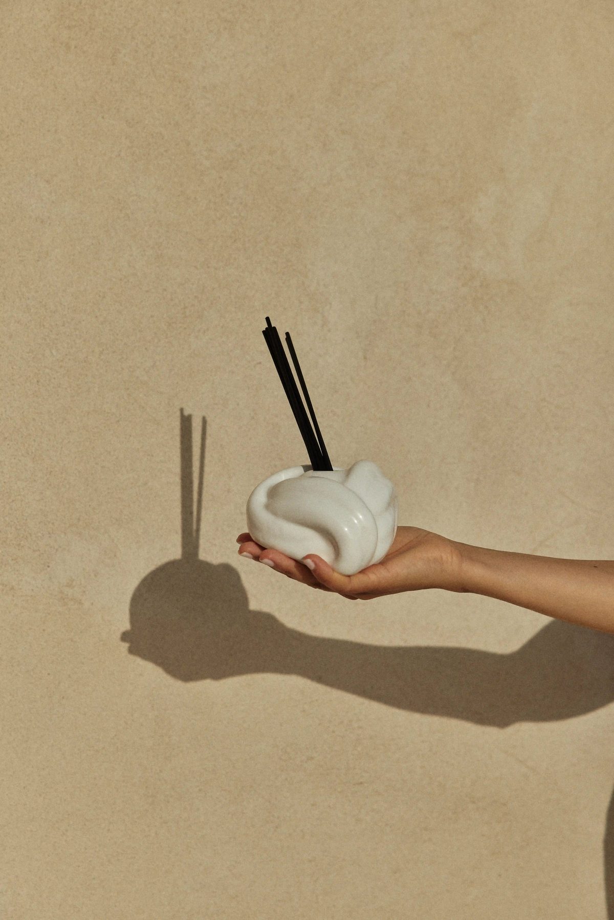 Zaaman ceramic vessel held in hand, sunlit wall